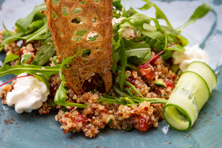 Healthy Italian salad of quinoa seeds, tomatoes and arugula with cream cheese and toast. Haute cuisine in the restaurant on the street terraceの写真素材