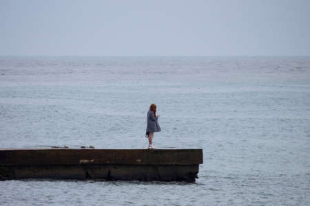 in the summer, a girl with long hair stands on the pierの写真素材