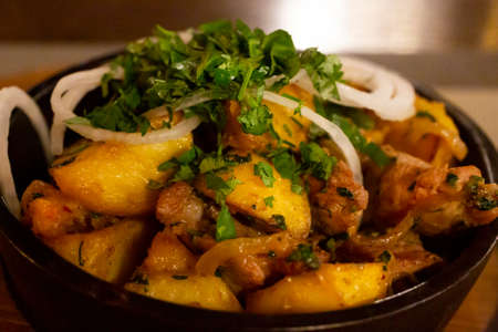 a frying pan with potato meat and fried onions on a wooden table. the concept of Caucasian and Russian cuisine. potatoes, fried in a frying panの写真素材
