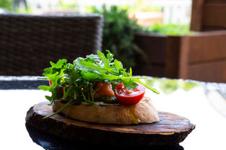 Italian tomato bruschetta with chopped vegetables, salmon, herbs and butter on fried or toasted...