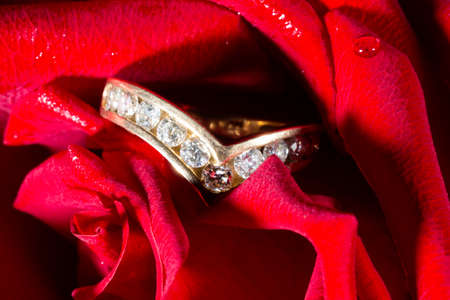 Diamond engagement ring with a path of diamonds and a red rose. The concept is an offer to become my wifeの写真素材