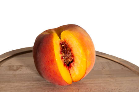 Peaches on a wooden board. Peach in half with a stone. Ripe fruitsの写真素材