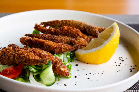 Fried fish smelled on the plate, served with lemon, grilled vegetables. Smelt-small sea fishの写真素材