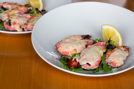 baked mussels with masago caviar and cheese on a white plate whit lemonの写真素材