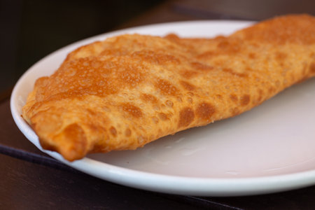 Chebureks with meat on a plate on a wooden table. Big chebureks for dinner. Meat pies. A hearty lunch.の写真素材