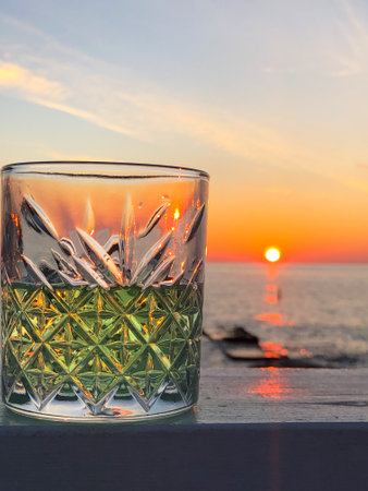 a glass of on the table at sea sunset close upの写真素材