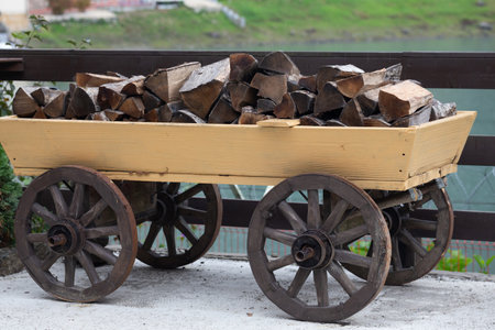 The firewood is lying on an old wooden cart. Preparation for the winter heating season. Firewood for the fireplace and stove. Natural fuel conceptの写真素材