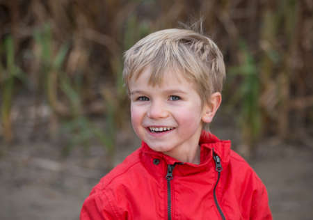 portrait of a charming toddler boy in red jacket with a cute smile. looks into frame. Good mood for...