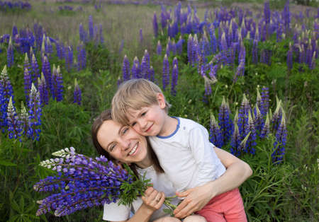Family weekend leisure. Happy mom and cute son are hugging among the wildflowers in the field. Maternal happiness. Rest at nature. Mothers dayの写真素材