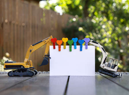 Two models of toy excavators are holding a blank sheet of paper for text. space for announcement, advertising, business - congratulations to the construction companyの写真素材