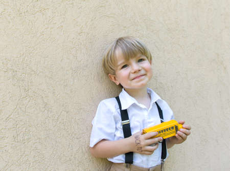 Back to school concept. Yellow model of a toy school bus in hands of a cheerful cute schoolboy...