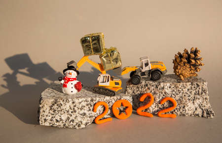 models of toy orange excavators stand on pieces of granite, a souvenir snowman, figures of the new...