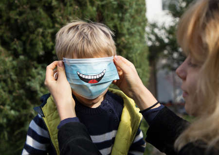 Drawn funny smile on a blue anti-virus mask. A fun DIY face mask for safety in a pandemic or...