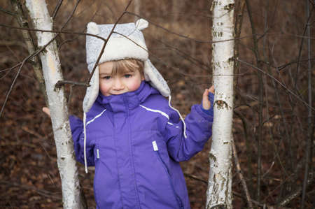 portrait of a 4 year old European boy in a gray winter fur hat and purple jacket on a walk in the...