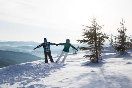 unrecognizable couple in love in warm clothes against backdrop of picturesque snowy landscape in...