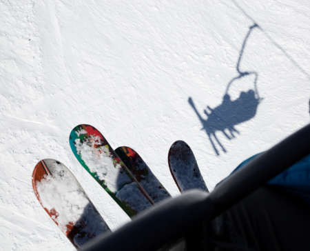 two pairs of skis, people on the lift climb the snow-covered mountain slope. cold winter sunny day....