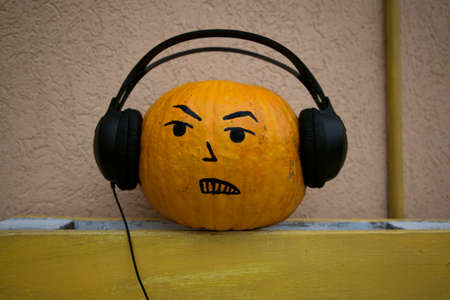 Halloween Orange pumpkin with big black headphones and a painted grinning face