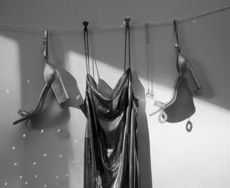 elegant festive outfit set for lady. Silver women's high-heeled shoes, dress with thin straps, ladies handbag. play of shadows and light. Black and white photoの写真素材