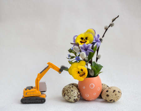 model of toy excavator with Easter composition of spring flowers and eggs. Easter holiday concept for construction companies. postcard. Selective focusの写真素材