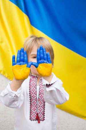 Children's hands are painted in the colors of the Ukrainian flag. child's request to stop the war in Ukraine. national independence. Children against warの写真素材