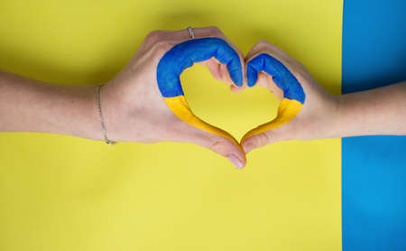 women's and children's hands join in shape of a heart painted in yellow and blue colors of Ukrainian flag. Family, patriotism, unity, support. asking for help from the world community. Stay with Ukraineの写真素材