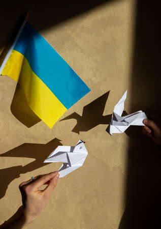 2 paper doves of peace and Ukrainian flag. Stand with Ukraine. Stop the war in Ukraine. Appeal to...