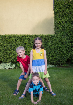 Portrait of three small children in a park on green grass, looking at the camera. During the summer, siblings spend time outdoors. Friendship, childhood, joy, holidays. copy spaceの写真素材
