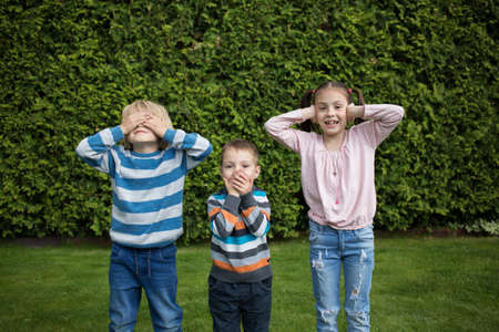 Three children visually show the concept - see nothing, say nothing and hear nothing. Interesting childhood, useful behavioral skillsの写真素材