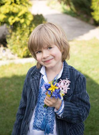 smiling Ukrainian boy 5 years old in vyshyvanka. Holds flowers for mom, warrior. Pride, freedom, independence, gratitude. Victory day. Peace to Ukraine. Stop Russian aggressionの写真素材