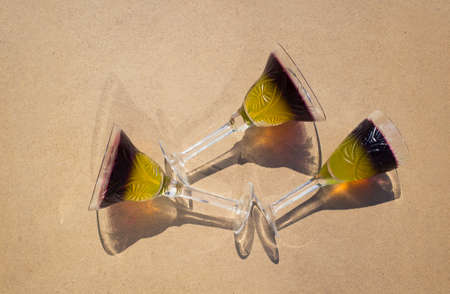 3 crystal glasses with two-color fruit jelly lie on a beige background, top view. Bright sun, interesting shadows. Holiday and fun atmosphere. Delicious summer refreshing dessertsの写真素材