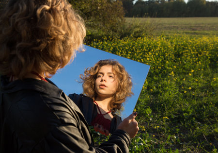 Sensual portrait of a beautiful teenager girl 17 - 18 years old. reflection in the mirror. Youth, beauty, self-confidence. through the looking glassの写真素材