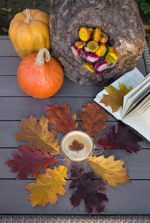 I love autumn, coffee and books. an open book, a cup of cappuccino among a collection of colorful bright fallen oak leaves. autumn atmosphere. education conceptの写真素材
