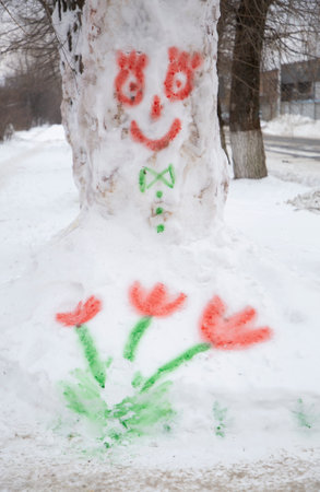 Children's drawing with multi-colored paints on the snow, painted flowers and a funny face. Goodbye winter, hello spring. Educational winter games. Fun family pastime, ideas for creativityの写真素材
