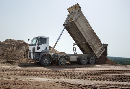 gray dump truck at the construction site in the process of transporting soil unloading. excavation. commercial vehicle for construction businessの写真素材