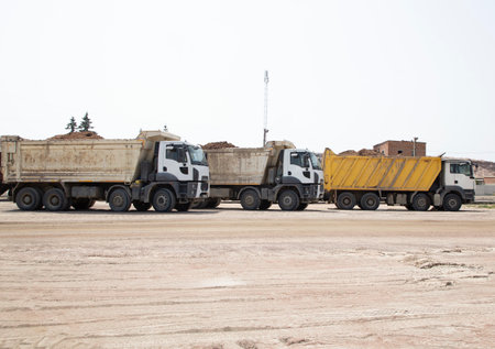 three dump trucks standing in a row at a construction site. The process of transporting and unloading soil on a construction machine. excavationの写真素材