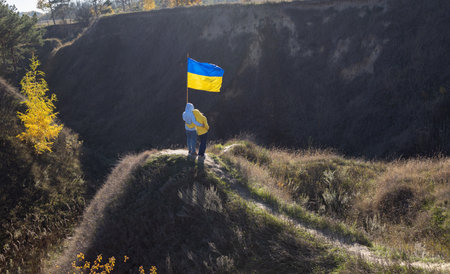 unrecognizable man and woman stand next to each other in picturesque place with large yellow blue...