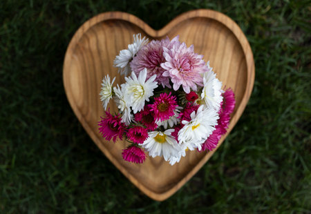 Wooden heart with pink, white chrysanthemum flowers. view from above. Flower surprise for mother's day, birthday, valentine's dayの写真素材