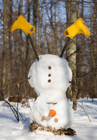 sad snowman turned upside down. goodbye winter concept. spring is coming. Unexpected March snow. Fun carefree fun. playing with snowの写真素材