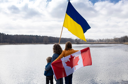 woman with children with Ukrainian and Canadian flags stand together in nature. International assistance to Ukraine, thanks from Ukrainians for their support. stop war. refugee and immigrant issuesの写真素材