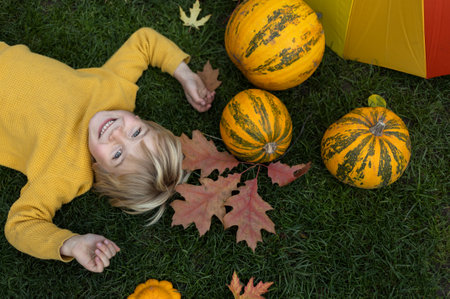 on the grass lies a boy, a bright yellow pumpkin, fallen multi-colored leaves, an umbrella. hello...