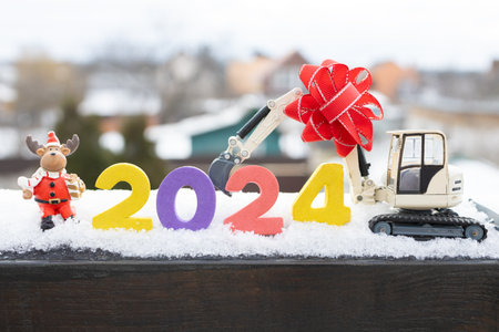 model of a toy excavator, souvenir deer, New Year 2024 numbers in the snow. card for Christmas business greetings in construction companies. Humor. winter holiday mood cardの写真素材