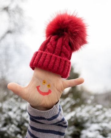 smiling face is drawn on the child palm, and a warm red knitted hat is put on his fingers. It's time...