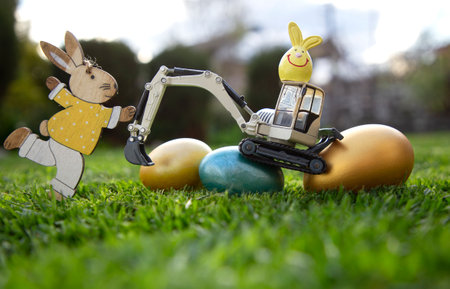 excavator, painted eggs, and decorative Easter bunnies standing on the grass