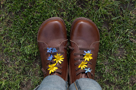 women's brown leather boots on grass. Blue and yellow flowers stick out among laces. spring walk for pleasure, energy of nature, freedom, active lifestyle. view from above. Hi spring. Earth Dayの写真素材
