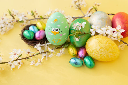 Easter colored eggs and colorful eggs in a nest in a small nest and spring white flowering branches...