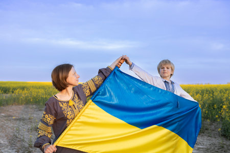 portrait of a Ukrainian family, mother and son with a blue-yellow flag against the backdrop of a blooming rapeseed field. Ukraine's Independence Day. support Ukraine. Stop the warの写真素材