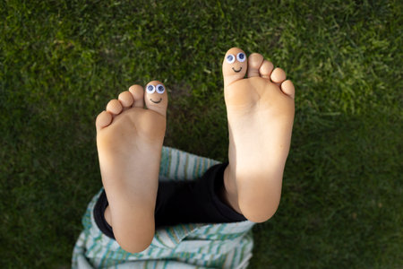bare feet of child with funny faces painted on big toys. positive atmosphere, humor, happy...