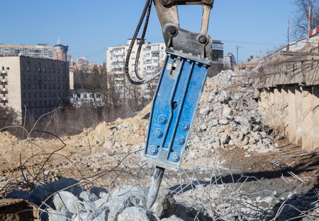 industrial hydraulic hammer at construction site performs work on dismantling reinforced concrete...