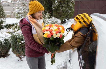 the boy looks out of the car window and hands his mother a large bouquet of many roses. A pleasant floral surprise with love for your beloved mommy. Winter timeの写真素材