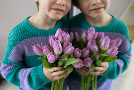part of face of cute boy near mirror with bouquet of pink lilac tulips. selective focus, reflection. Genderness of childhood. Festive mood, gift with love to mom, grandmother. Happy Mother's Day.の写真素材